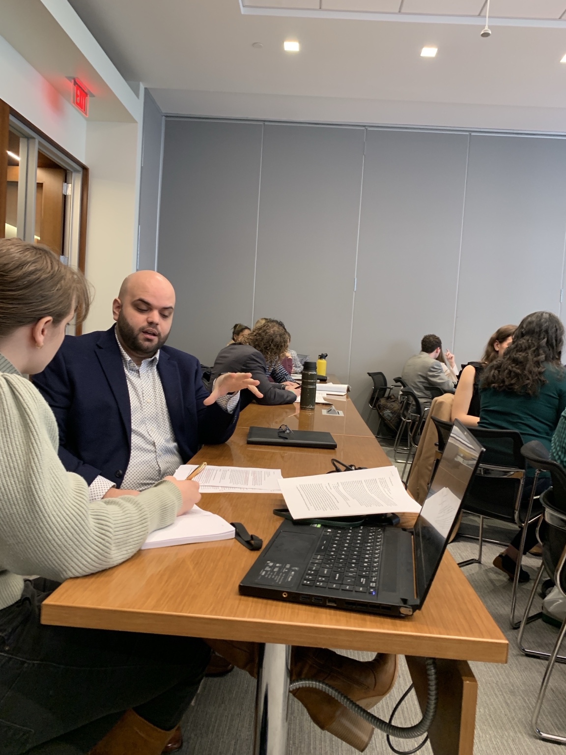 Taylor discussing coursework with a student at a classroom table